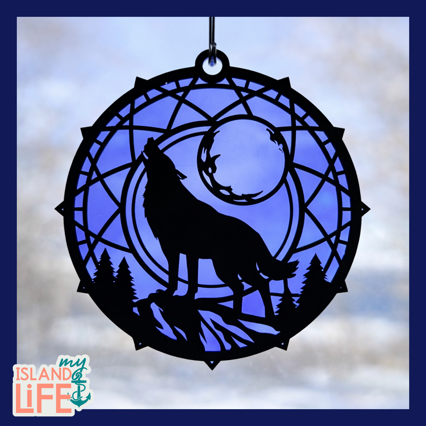 Decorative glass panel with a wolf howling at the moon design, set against a blurred natural background.