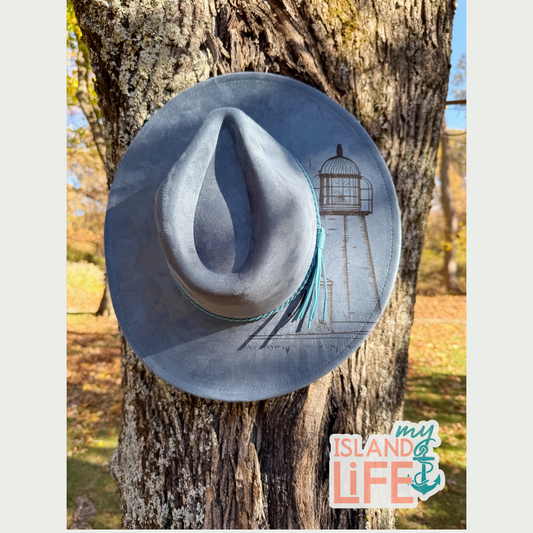 Blue cowboy hat with a lighthouse design on a tree trunk, featuring 'My Island Life' logo.