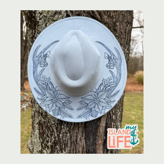 White cowboy hat with winter antlers and floral on a tree trunk, featuring 'my Island Life' logo.