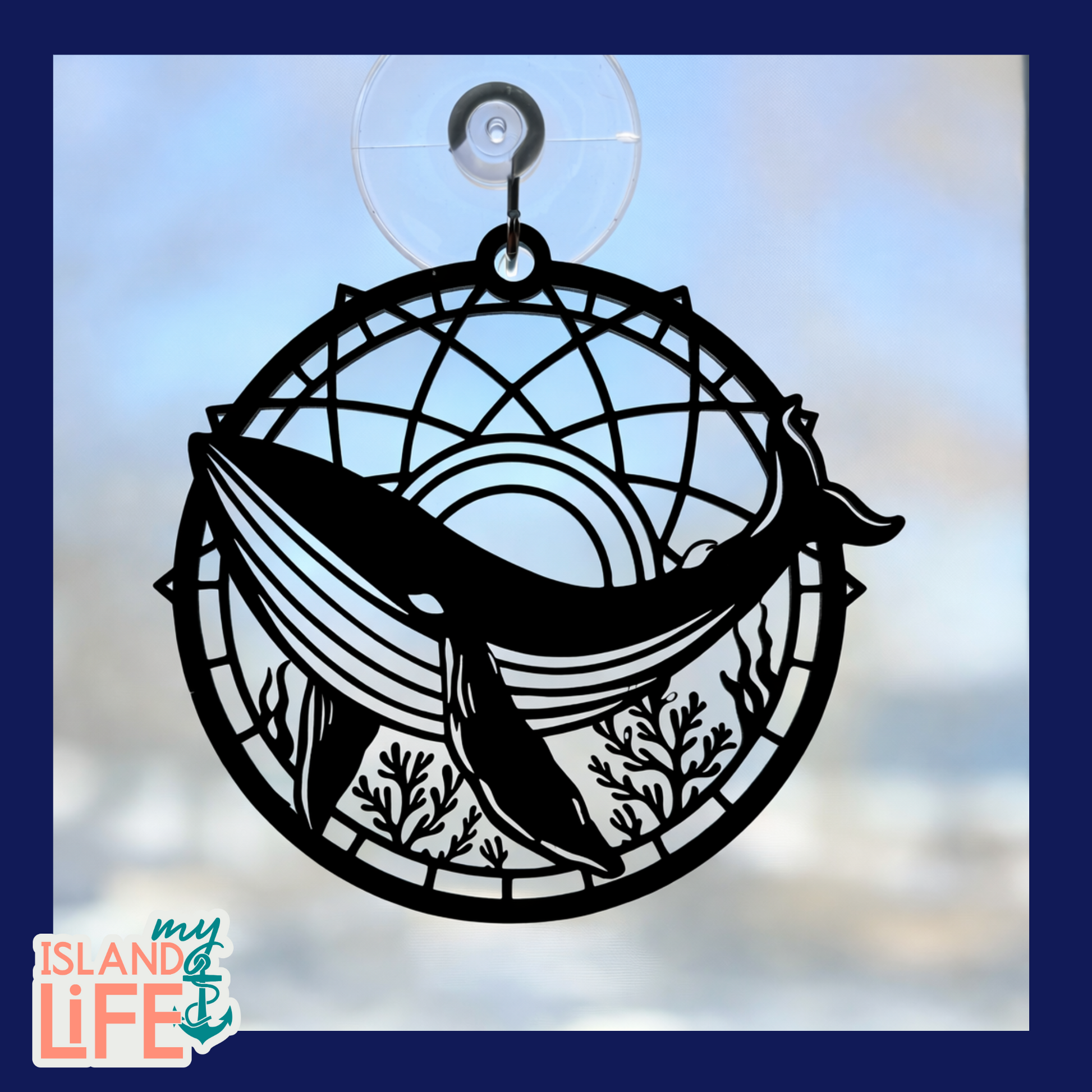 Decorative window decal with whale design and dreamcatcher pattern on a blurred background.