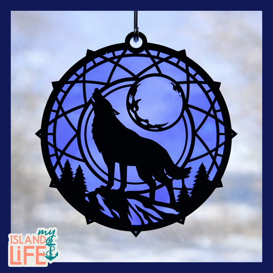 Decorative glass panel with a wolf howling at the moon design, set against a blurred natural background.